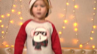 Yüzünde yeni yıl pijamalarıyla ve şapkasıyla gülümseyen küçük bir kız.