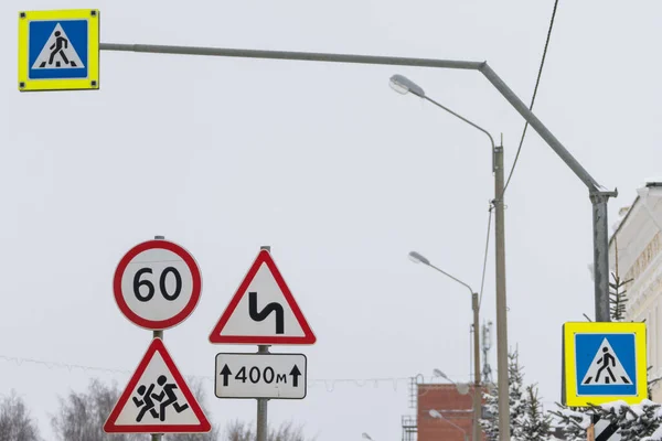 road signs stand side by side. a sign Overtaking is forbidden, the speed limit sign. the sign indicates that the road has turns for several hundred meters. pedestrian crossing signs with night