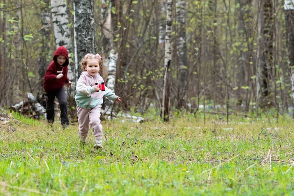 Brat i siostra prowadzą wyścig na polanie w lesie — Zdjęcie stockowe