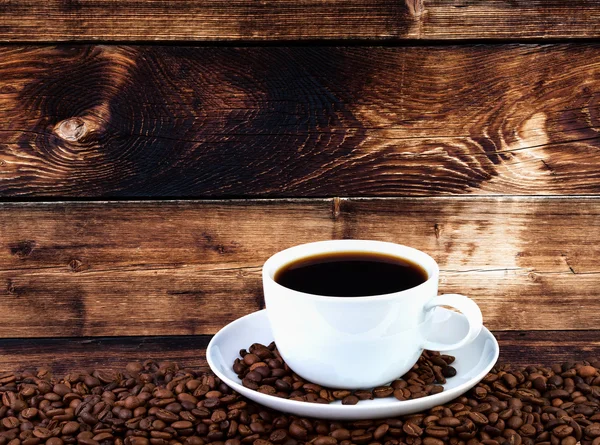 Šálek kávy s zrna na dřevěné pozadí. Kopie místo pro váš text. — Stock fotografie
