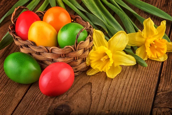 Colorida decoración de Pascua con huevos en cesta sobre mesa de madera oscura . — Foto de Stock