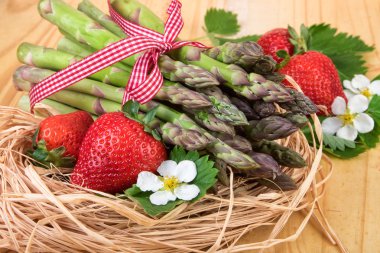 Yeşil kuşkonmaz ile çilek bir saman içinde iç içe. Retro natürmort.