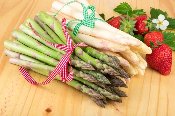 Grüner weißer Spargel mit frischen Erdbeeren auf hellem Holz. Veganes Essen, vegetarisches und gesundes Kochkonzept. — Stockfoto