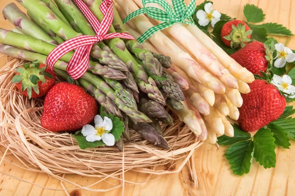 Grüner und weißer Spargel mit Erdbeere im Strohnest. — Stockfoto