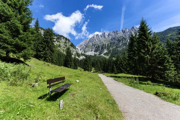Idéntica escena montañosa con un banco en primer plano. Alpes austríacos, Tirol, Wilder Kaiser — Foto de Stock