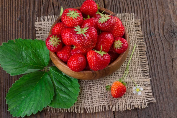 Biologische aardbeien in kom op oude houten achtergrond — Stockfoto