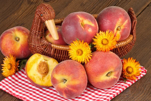 Peaches in vintage basket on checkered red tablecloth-autumn still life — Stok fotoğraf