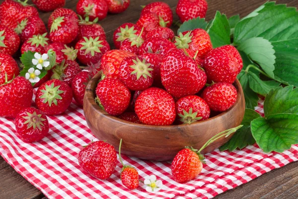 Reife Erdbeere in Holzschale auf rot karierter Tischdecke — Stockfoto