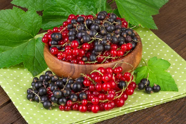 Bayas de grosella roja y negra en cuenco de madera — Foto de Stock