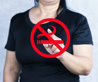 Sigara içilmeyen kırmızı bir tabelanın fotoğrafı bir kadının elinin üzerine yerleştirilmiş ve tabelayı gösteriyor..