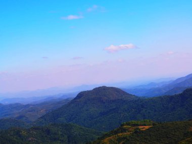 Gökle çelişen, yemyeşil ormanlarla kaplı engebeli bir dağ manzarasının fotoğrafı..