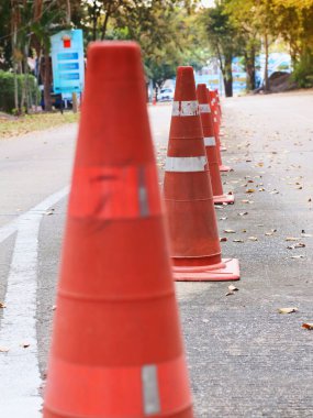 Yansıtıcı şeritli turuncu trafik konileri asfalt yolda kapanış ya da inşaat alanını belirtmek için dizilmiştir..