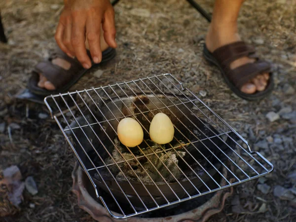 Görüntü, iki tavuk yumurtasının, dışarıdaki küçük kömür ızgarasının üzerinde ızgara yapıldığını gösteriyor..