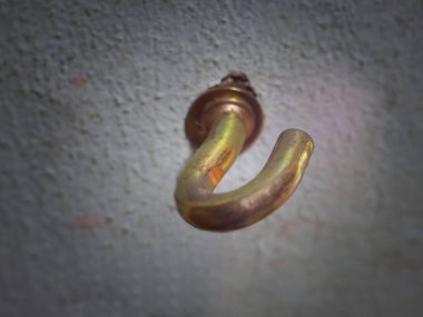 Gri bir duvara takılmış altın bir kancanın ayrıntıları.