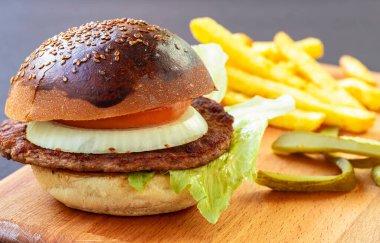 Tahta arka planda patates cipsi ve hamburger.
