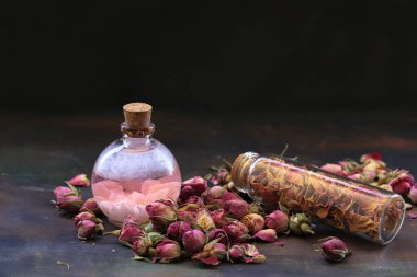 Masada küçük gül tomurcukları ve şişede gül yağı..