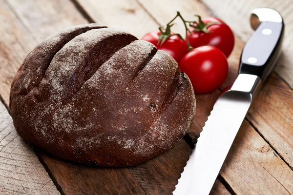 Bochenek chleba, pomidory i nóż — Zdjęcie stockowe