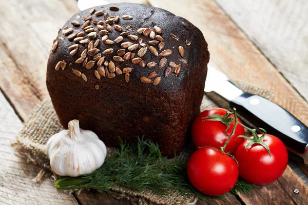 Bochenek chleba, nóż i warzywa — Zdjęcie stockowe
