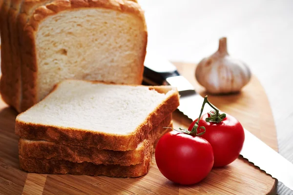 Toast op het bord, garlik mes en tomaten — Stockfoto