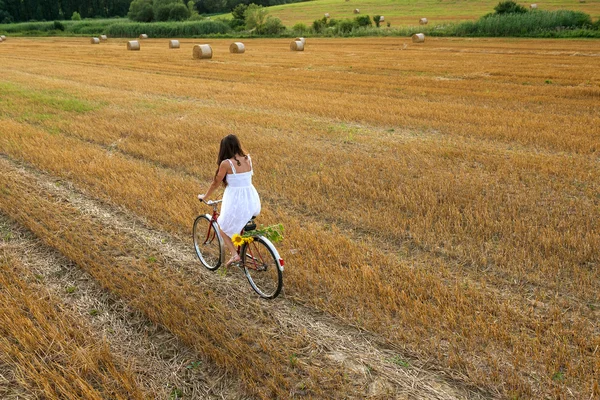 Mujer con bicicleta vieja en campo de trigo — Foto de Stock