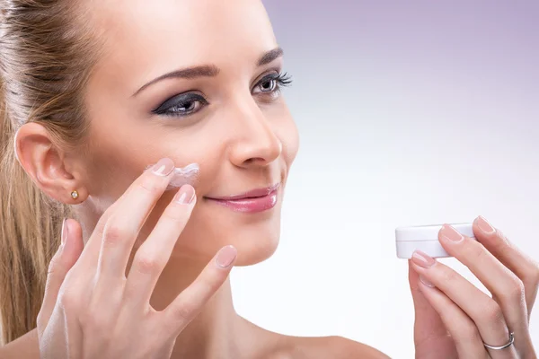 Woman applying cream on face — Stock Photo, Image