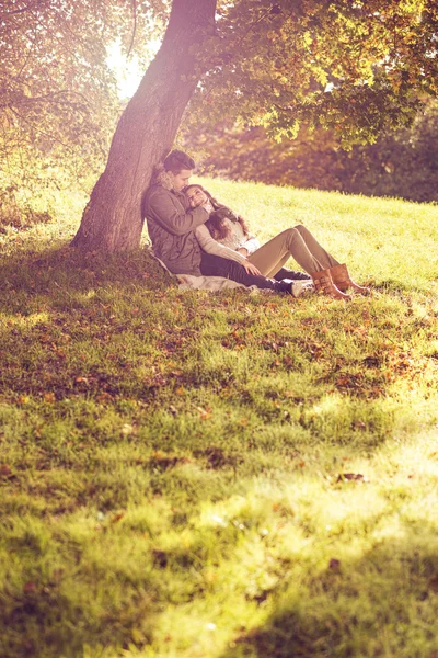 Paar sitzt unter Baum — Stockfoto