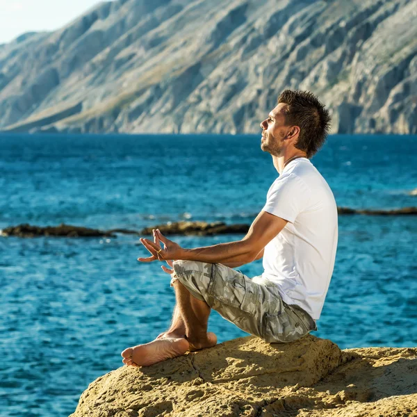 Man in yoga position on beach — Stock Photo, Image