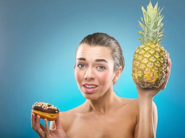 Woman choosing between pineapple and donut — Stock Photo, Image