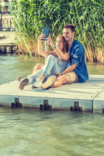 Verliebtes Paar sitzt auf Seebrücke — Stockfoto