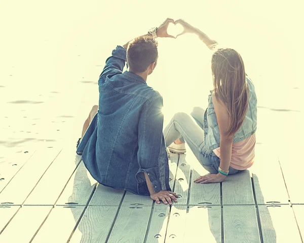 Pareja enamorada sentada en el muelle Imagen De Stock