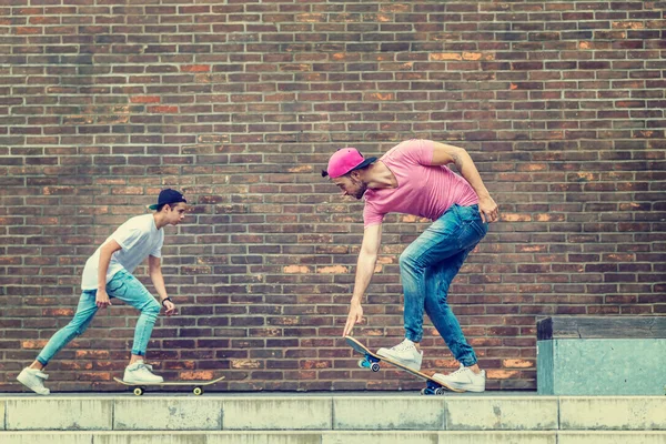Skateboarders por parede de tijolo — Fotografia de Stock