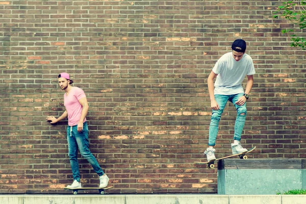 Skateboarders door bakstenen muur — Stockfoto