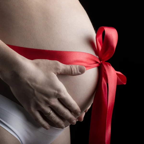 Kobieta w ciąży z owinięte wstążki na brzuch — Zdjęcie stockowe