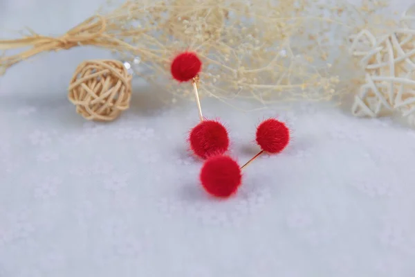 赤いポンポンのイヤリングは 2つのふわふわのボールのような形をしています イヤリング以外にも籐製品や花束の標本があります これらのアイテムはチュールに配置されます イヤリングは非常に美しく ファッショナブルな外観 — ストック写真