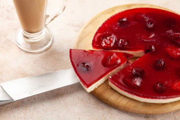 Домашний вишневый и клубничный чизкейк, чашка латте с макиато, кусочек пирога на ноже — стоковое фото