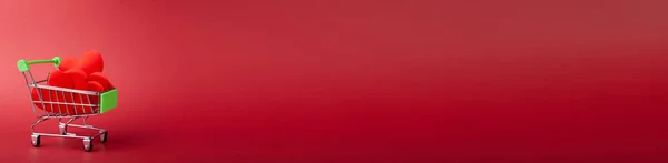 ミニ食料品店のカートの中に赤いハートのバナー、赤い背景にショッピングバケツ — ストック写真