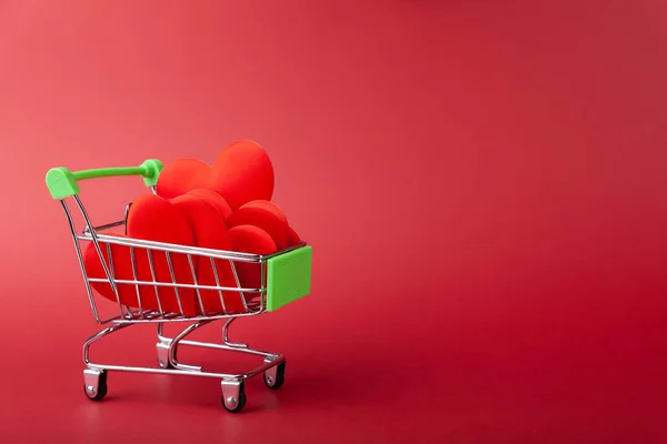 ミニ食料品のカートで心のヒープ,赤の背景に,ショッピングと愛の概念 — ストック写真