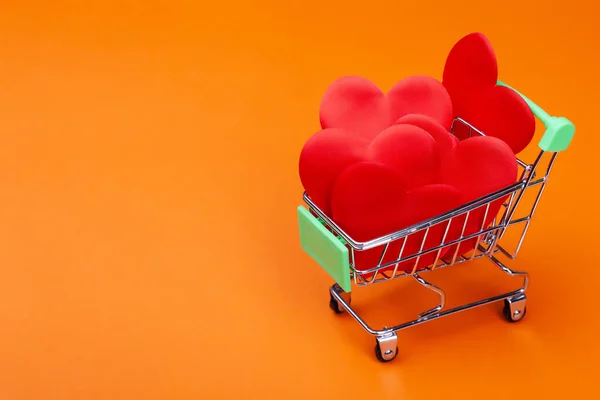 カラフルな背景にミニ食料品店のカートの中に多くの赤い心 — ストック写真