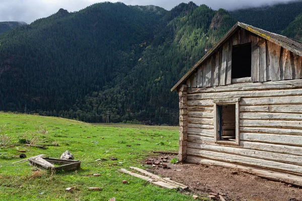 Beautiful wooden abandoned log house on mountains background — Stock Photo, Image