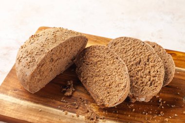 Yakın plan taze doğranmış çavdar ekmeği, tahta kesme tahtasında dilimler.