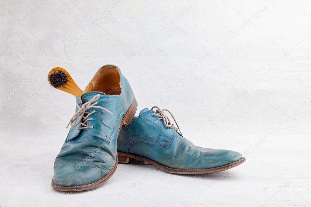 Pair of old leather blue boots with laces with shoe brush