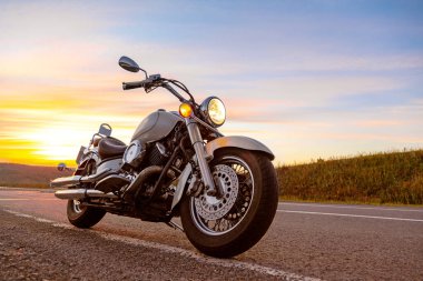 Klasik motosiklet helikopteri, boş asfalt yolda kruvazör gün batımında gökyüzü arka planında.