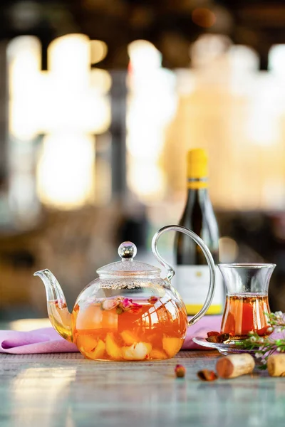 Frutas transparentes bule e xícara de chá, garrafa de vinho e estantes de cortiça na mesa — Fotografia de Stock