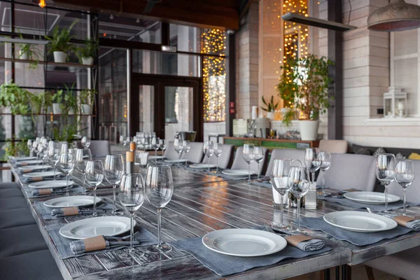 Modern veranda restaurant interior, banquet setting, glasses, plates