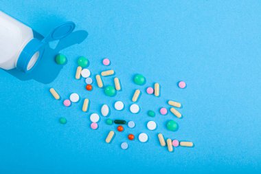 İlaç şişesi renkli tablet ve kapsüllerden yayılmış çeşitliliğin üst görünümü