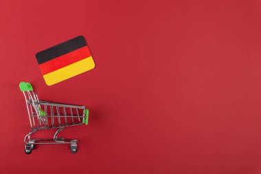 Mini boş süpermarket market arabası, kırmızı arka planda Almanya bayrağı