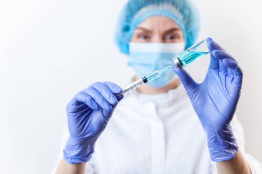 Şırıngayı aşıyla, ilaçla dolduran eldivenli doktor.