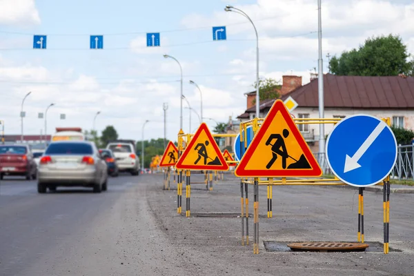 Asfalt wegreparaties, gele waarschuwingsdriehoek borden over wegwerkzaamheden en bypass richtingen — Stockfoto