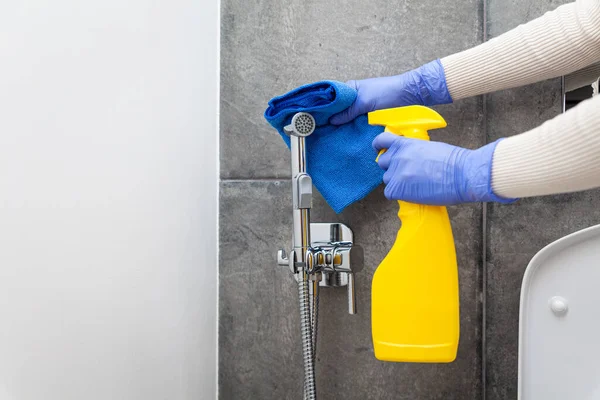 Manos en guantes protectores limpiando la ducha higiénica en la habitación sanitaria Fotos de stock