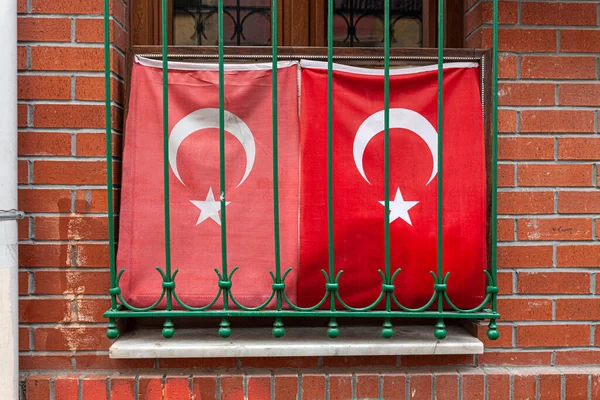Två viftande turkiska flagga i fönster med galler, tegelvägg — Stockfoto